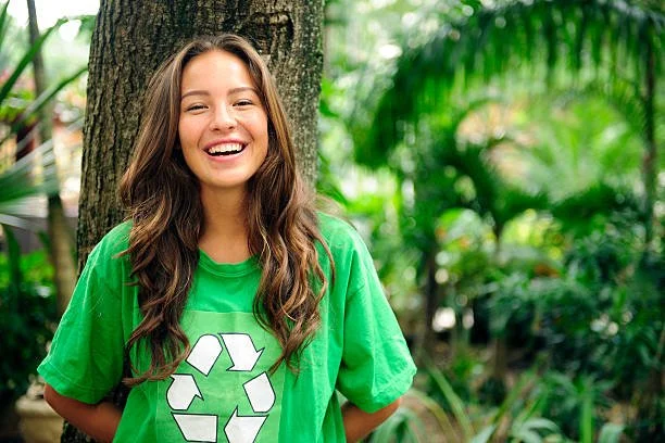 Girl wearing a T-shirt with a recycling logo, illustrating the psychology of eco-friendly choices and promoting sustainable practices like Terra Tag’s plantable and recycled name badges