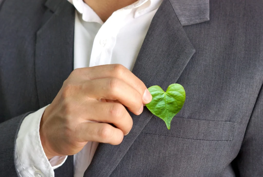 Man placing a heart-shaped leaf in his suit pocket, symbolising corporate responsibility and sustainability, aligned with Terra Tag’s eco-friendly name badges and event practices