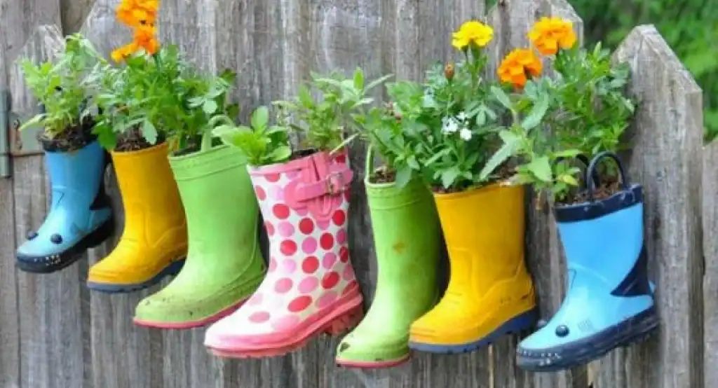 Rubber boots repurposed as plant pots on a fence, illustrating the importance of upcycling and sustainable practices like Terra Tag’s plantable and recycled name badges