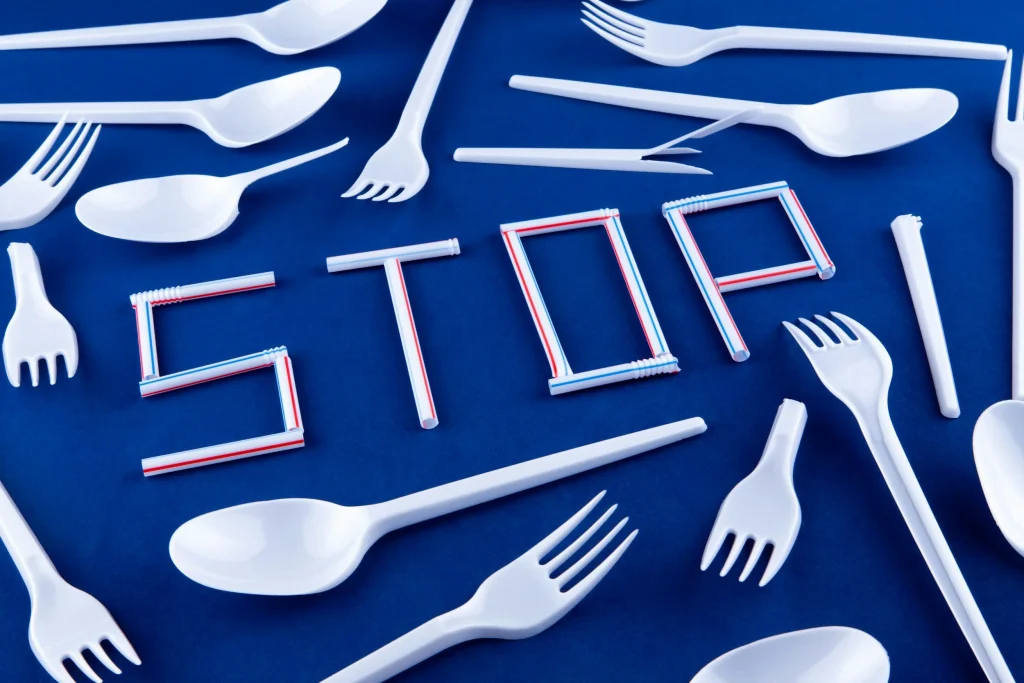 Plastic utensils with the word 'Stop' illustrating the need for sustainable alternatives at events, highlighting Terra Tag’s eco-friendly name badges and biodegradable supplies