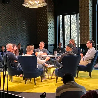 Government panel speakers wearing professionally printed recycled paper name badges during a formal conference session.