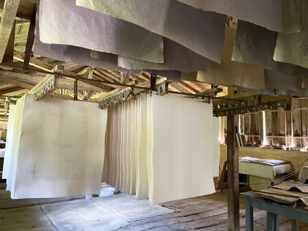 Sheets of handmade paper drying on a rack at home