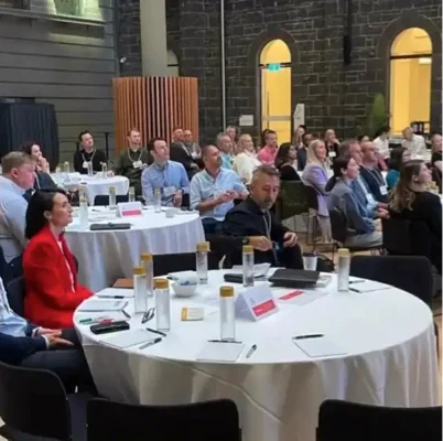 Attendees at a government forum wearing sustainable conference badges made from seed paper during a roundtable event.