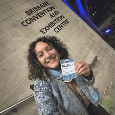 Guest wearing a seed paper conference badge at the Brisbane Convention and Exhibition Centre, showing the plantable name badge in use at a live event.